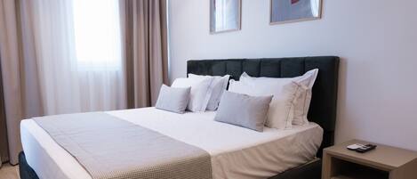 Una habitación de hotel moderna con una cama grande, una mesita de noche y dos cuadros enmarcados en la pared.