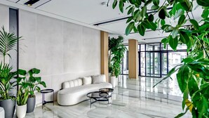 A modern lobby with a white sofa, a glass coffee table, and potted plants. - Bonita Luxury Resort & Spa (Golem)