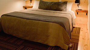 Un dormitorio con cama, cabecero de madera, ventilador de techo, ventana y mesita de noche con lámpara.