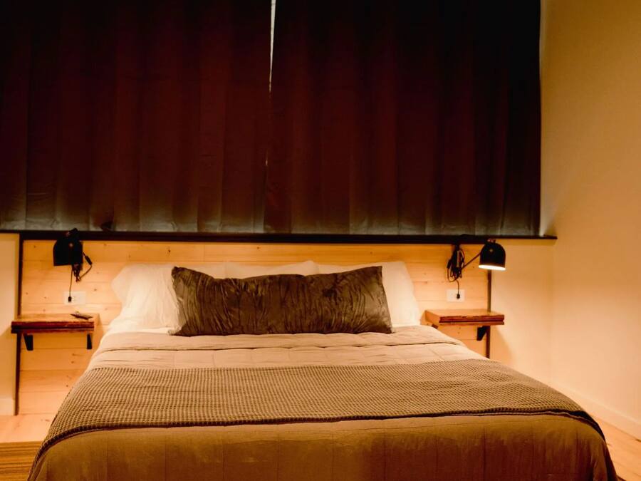 A bedroom with a bed, a ceiling fan, a window with curtains, and bedside lamps.