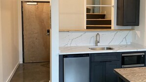Una cocina moderna con encimera de mármol, lavavajillas integrado y muebles oscuros.