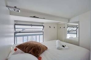 A modern hotel room with a large bed, a window with a view, a mirror, and a ceiling light. - Chic duplex loft in the heart of Paris Montorgueil (Paris)