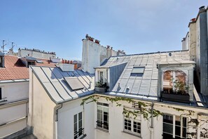 Un edificio de varios pisos con techo inclinado, ventanas de tejado y una chimenea visible.