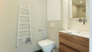 A bathroom with a white toilet, a wooden vanity, a mirror, and a white ladder against the wall. - lovely apartment center of Paris (Paris)