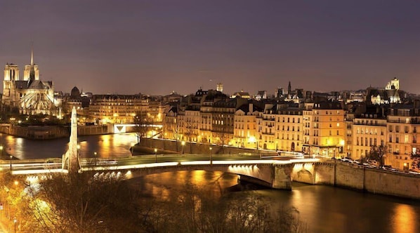 A nighttime cityscape with a prominent cathedral and a bridge over a river.