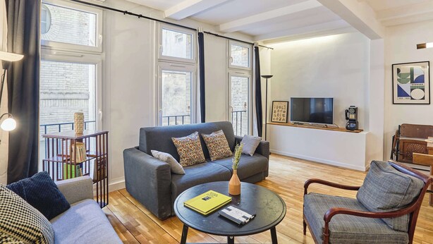 A modern living room with a grey sofa, a round coffee table, and a television on a stand. - Magnificent flat in Saint Germain des Près (Paris)