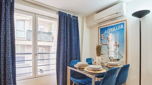 A dining area with a table set for four, blue chairs, a poster on the wall, and an air conditioning unit. - Sublime apartment Le Marais / Beaubourg (Paris)