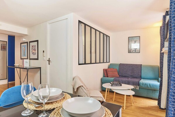 Un salon comprenant une table à manger, un canapé, une petite table basse et une porte donnant sur une autre pièce.