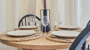 A round wooden dining table with four chairs, a vase with dried pampas grass, and wine glasses and plates set for a meal. - Sublim & NEW apartement St Germain/Notre Dame (Paris)
