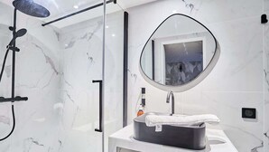A modern bathroom with a glass-enclosed shower, a round mirror, and a white marble backsplash. - New apartment Centre de Paris Bourse (Paris)