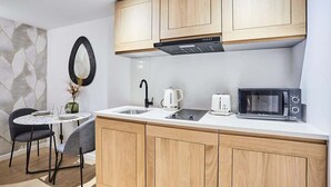 A modern kitchen with wooden cabinets, a microwave, a kettle, and a small dining table with chairs. - New apartment Centre de Paris Bourse (Paris)