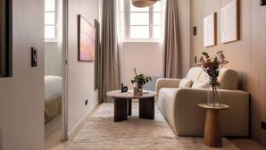 A modern living room with a sofa, a round coffee table, and a vase with flowers.