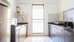 A modern kitchen with stainless steel cabinets, a black countertop, and a window with a view of buildings.