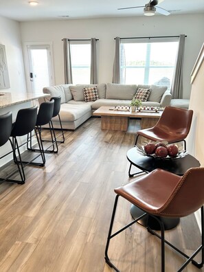 A modern living room with a sectional sofa, a coffee table, and a dining area with chairs.