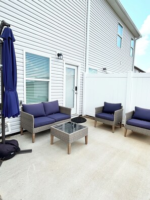 A patio area with wicker furniture and a glass coffee table.