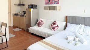 A hotel room with a bed, a sofa, a small kitchenette, and a chair. - Free Wifi and Netflix | The Linear Makati CRQ-1 (Makati)