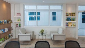 A modern waiting area with two sofas, a coffee table, and a bookshelf with magazines. - Free Wifi and Netflix | The Linear Makati CRQ-1 (Makati)