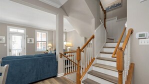 Un intérieur de maison avec un escalier, une rampe en bois et un canapé bleu.