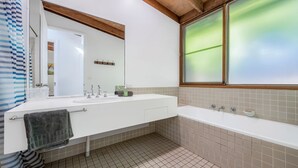 A modern bathroom with a white sink, a mirror, a bathtub, and a window with frosted glass. - Koalas at Links Lighthouse Beach (Port Macquarie)
