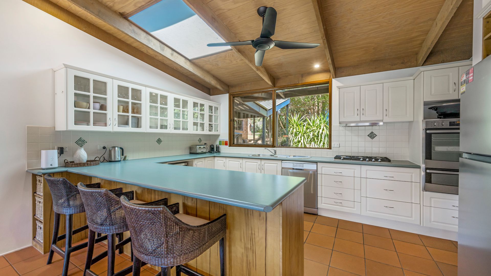 A modern kitchen with a central island, white cabinetry, and a ceiling fan.