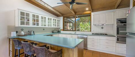 A modern kitchen with a central island, white cabinetry, and a ceiling fan.