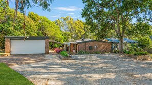 A residential property with a garage, a covered porch, and a gravel driveway.