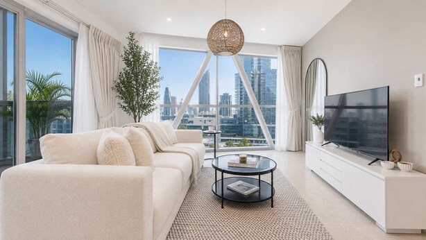 Ein modernes Wohnzimmer mit einer Couch, einem Couchtisch, einem Fernseher und Blick auf eine Skyline.