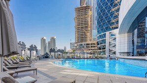 Pool auf dem Dach mit Liegestühlen und Blick auf moderne Gebäude.
