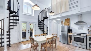 A modern kitchen with a central island, stainless steel appliances, and a spiral staircase. - Good Day Treehouse I Hot tub, stargazing (Wimberley)