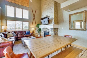 Un amplio salón con una gran mesa de comedor de madera, sofás de cuero y una chimenea de piedra.