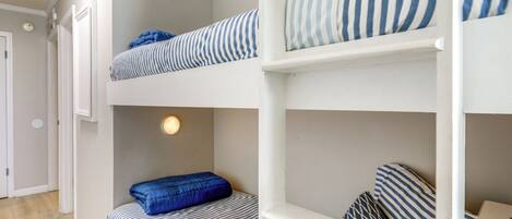 A bunk bed room with striped bedding and a wall sign that reads "Ride the Wave".