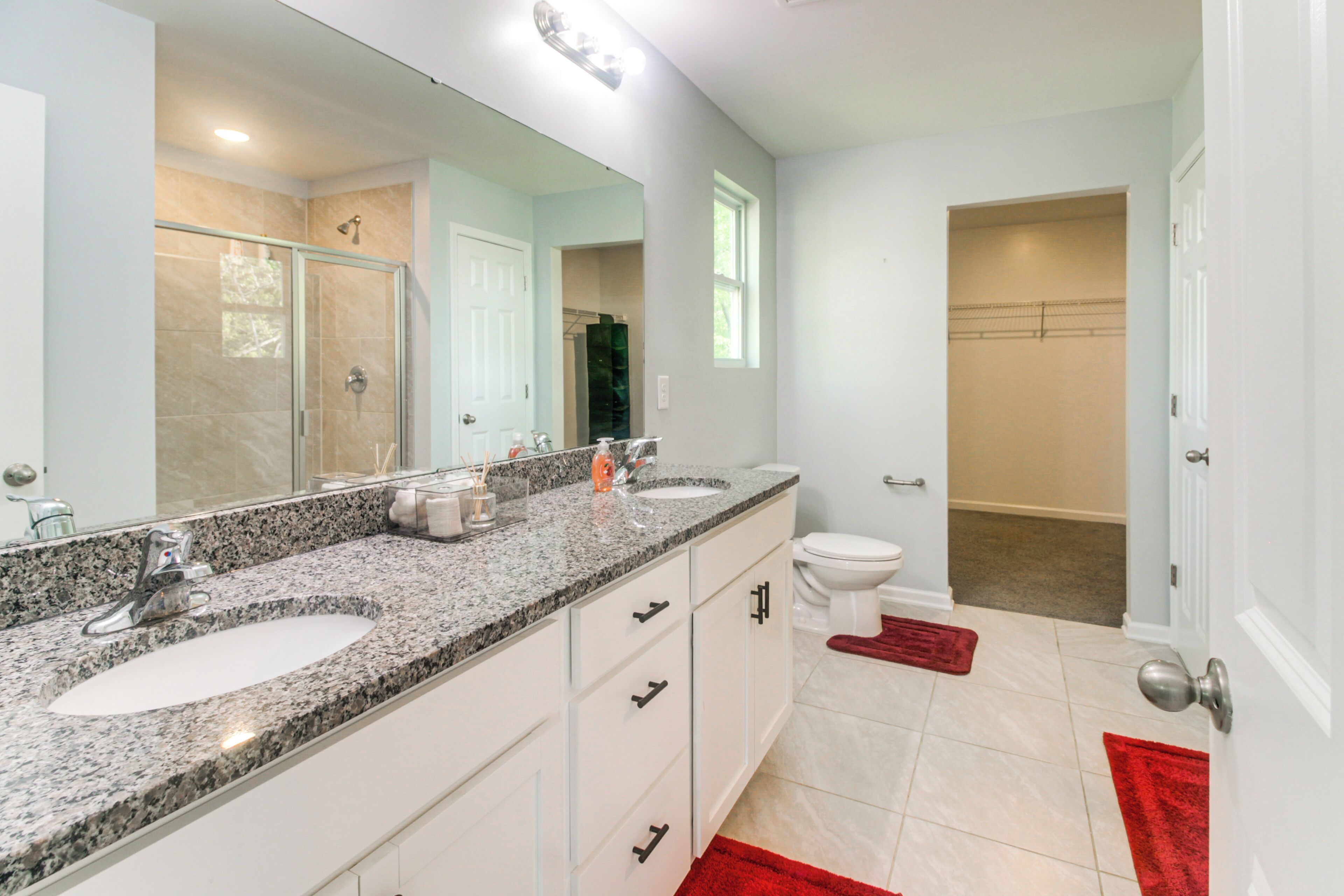 A modern bathroom with a double sink vanity, a large mirror, and a shower area.
