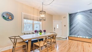 A dining area with a wooden table and chairs, a hanging light fixture, and a herringbone-patterned wall. - Play, Shop, Explore: Hidden Gem Near Lake Michigan (Charlevoix)