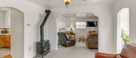 Amplia sala de estar con chimenea, sofás de cuero y ventilador de techo.