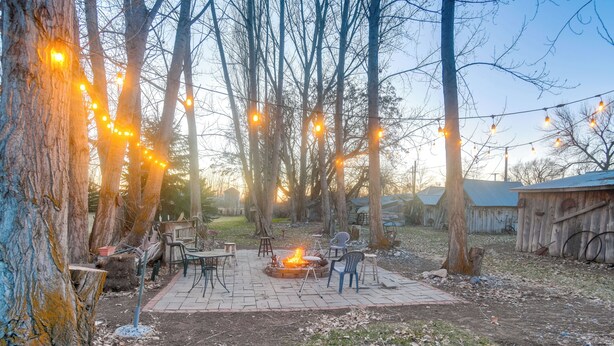 A backyard with a fire pit, outdoor furniture, and string lights. - Farmhouse w/ Horse Corral Near Wind River Arena (Rigby)