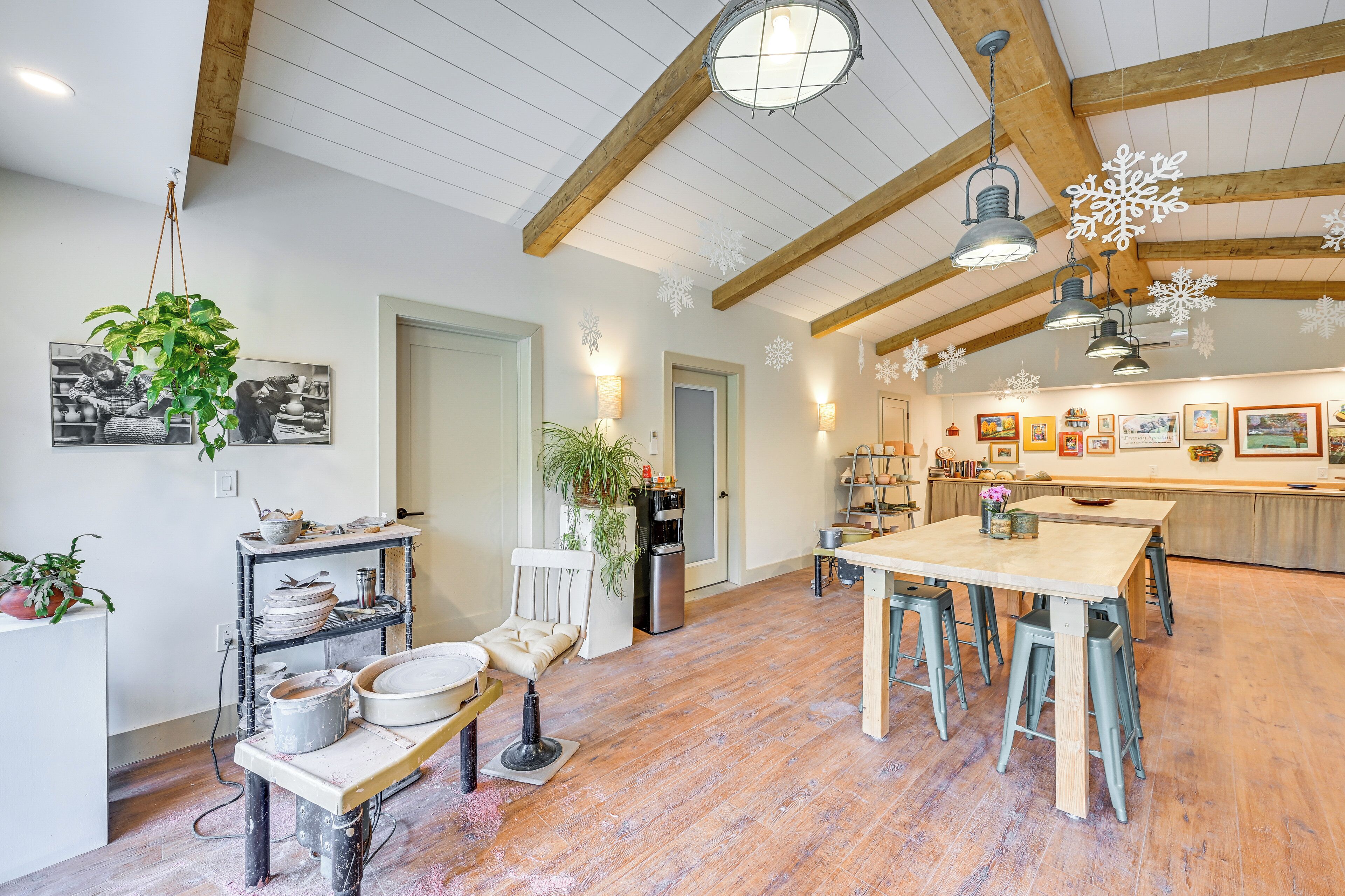 A spacious kitchen with wooden beams, a dining area, and a refrigerator.
