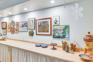 Una encimera con obras de arte enmarcadas, una decoración con forma de copo de nieve y diferentes utensilios de cocina.