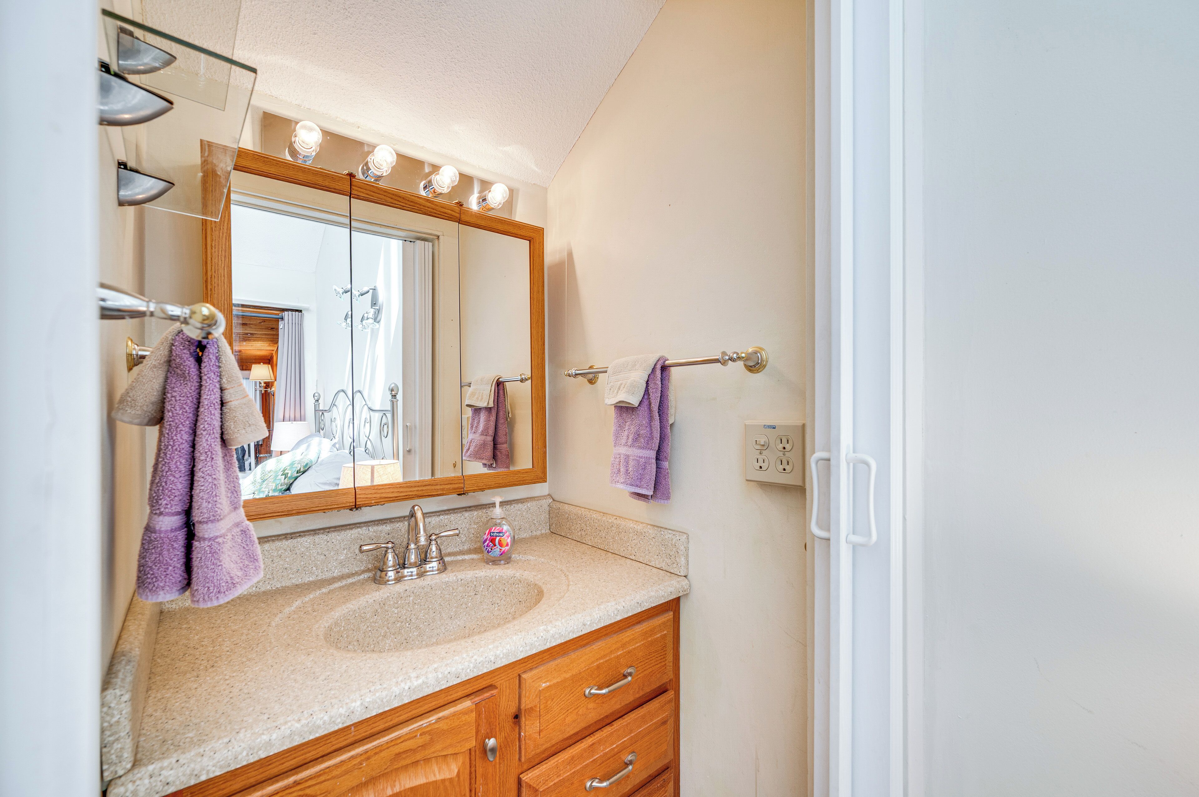 A bathroom with a large mirror, a sink, and wooden cabinets.