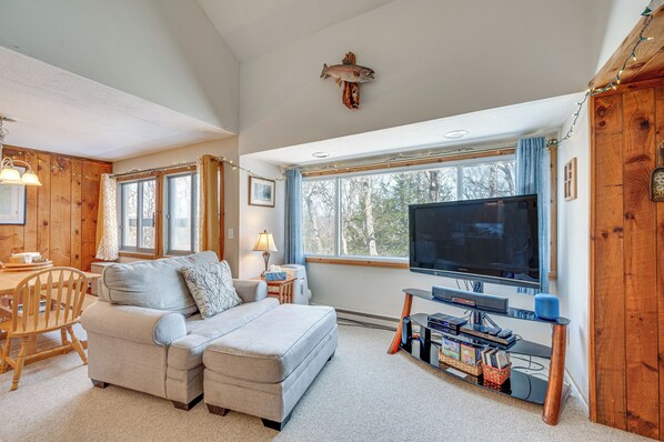 A cozy living room with a sofa, TV, and wooden walls. - Mountain Resort Condo With King Bed Suite (Campton)