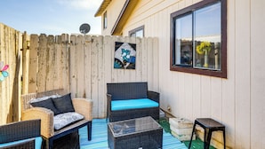 A patio with wicker furniture, a glass table, and a small stool.