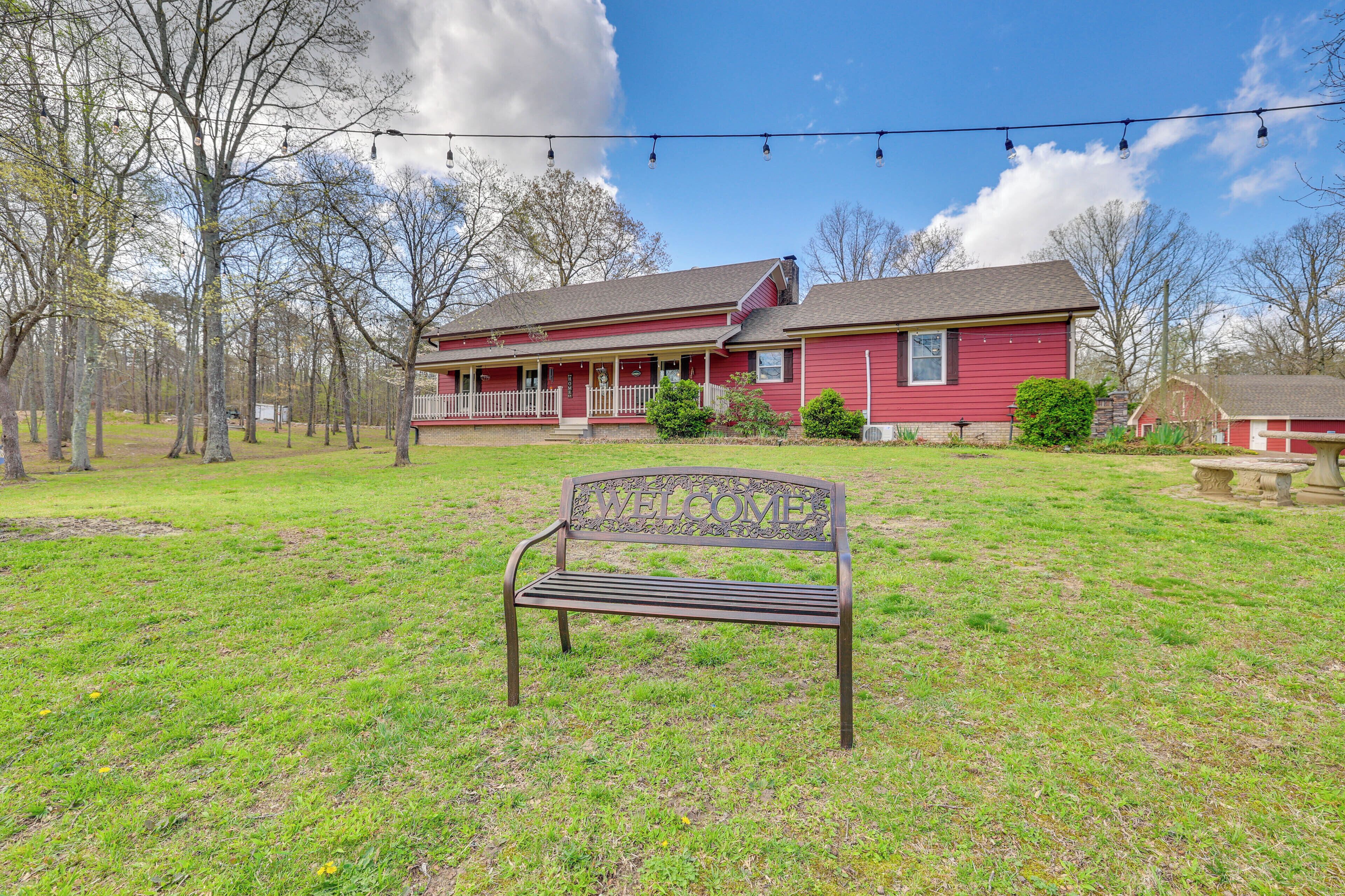 A red house with a porch and a bench in front.