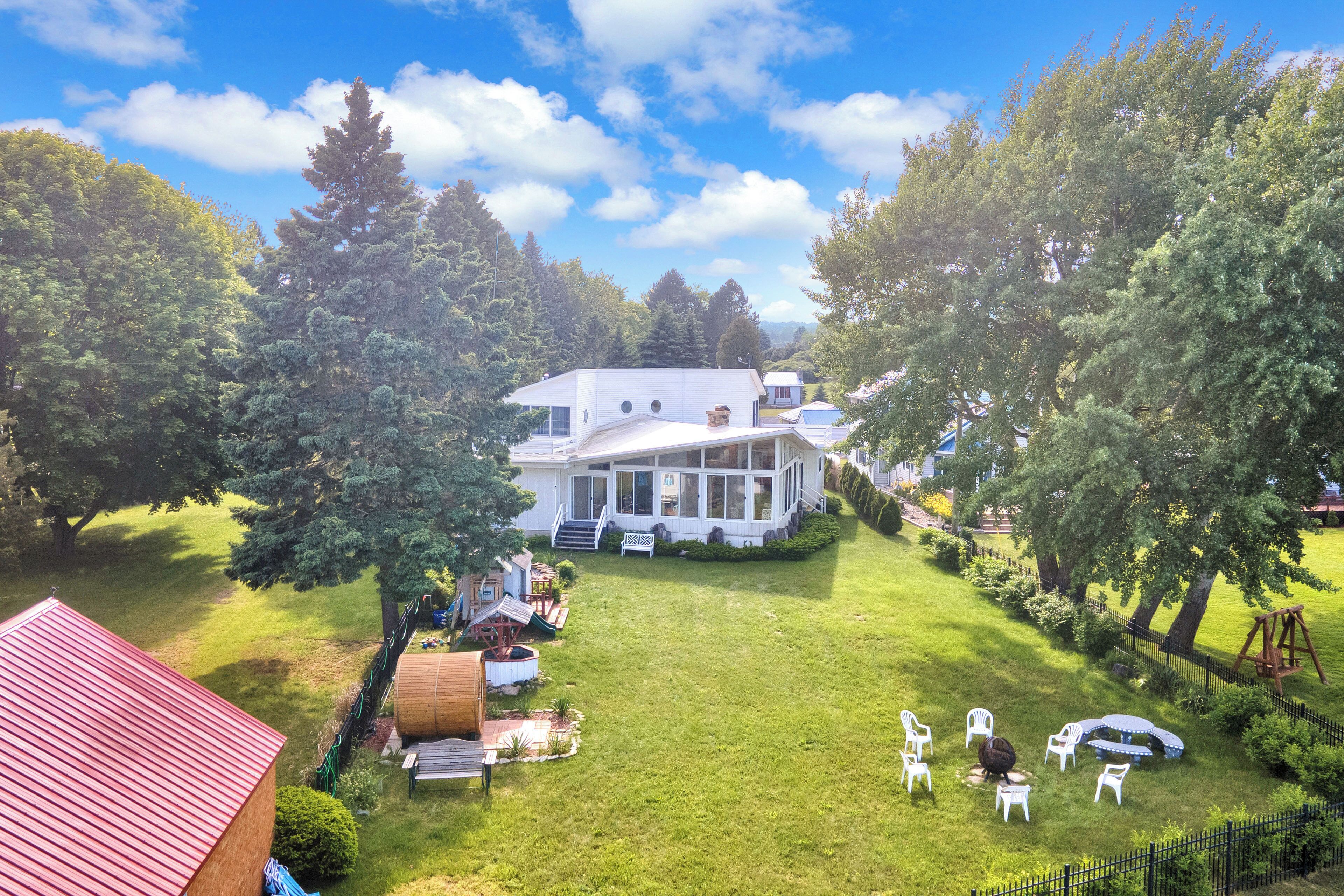 A large house with a spacious lawn, a covered patio, and a swing set.