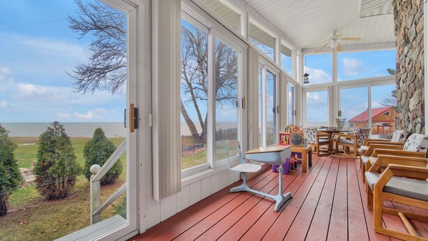 Eine überdachte Veranda mit Holzbänken, einem Tisch und Blick auf das Meer.