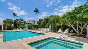 Ein Pool mit zwei Bereichen, umgeben von Palmen und Liegestühlen.