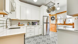 Une cuisine moderne avec des meubles blancs, un réfrigérateur en acier inoxydable et un carrelage décoratif.