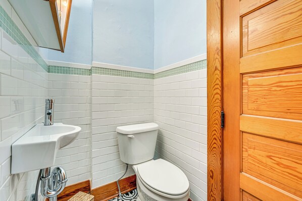 Une petite salle de bain avec des carreaux blancs, une porte en bois et des toilettes blanches.