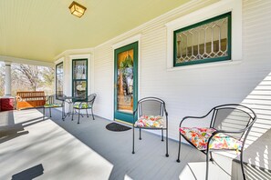 A covered porch with a table and chairs, a bench, and a door with a green frame. - Atlantic Farmhouse w/ Spacious Yard! (Atlantic)
