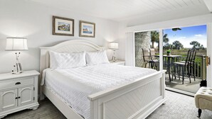 Une chambre à coucher avec un lit, des tables de chevet et un balcon doté d’un espace salon extérieur.
