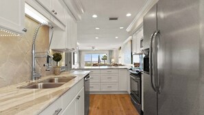 A modern kitchen with stainless steel appliances, white cabinetry, and a wooden floor. - Unbeatable location with Ocean Views, sleeps 6 (St Simons Island)