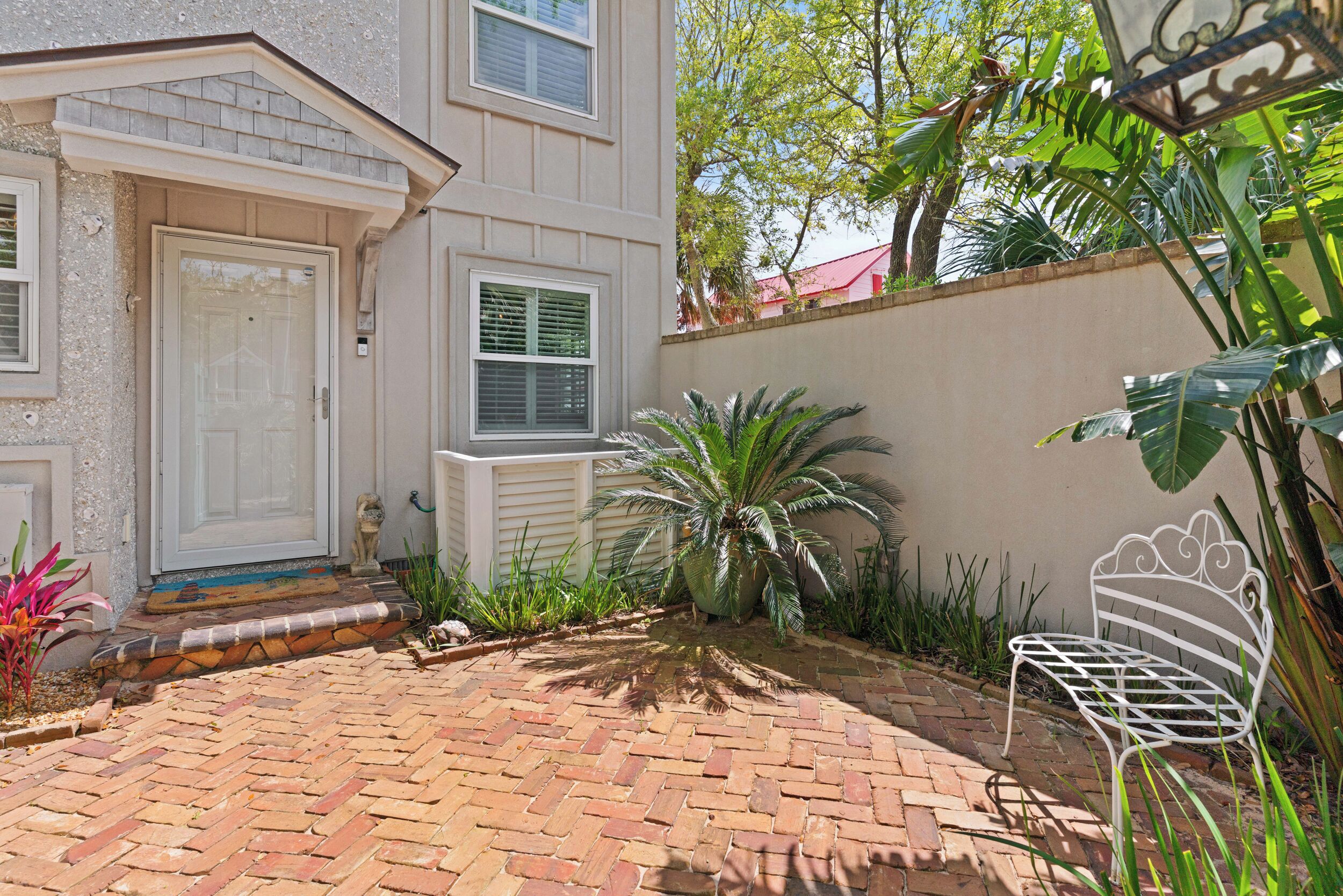 A brick patio with a white bench, a white door, and a small statue.